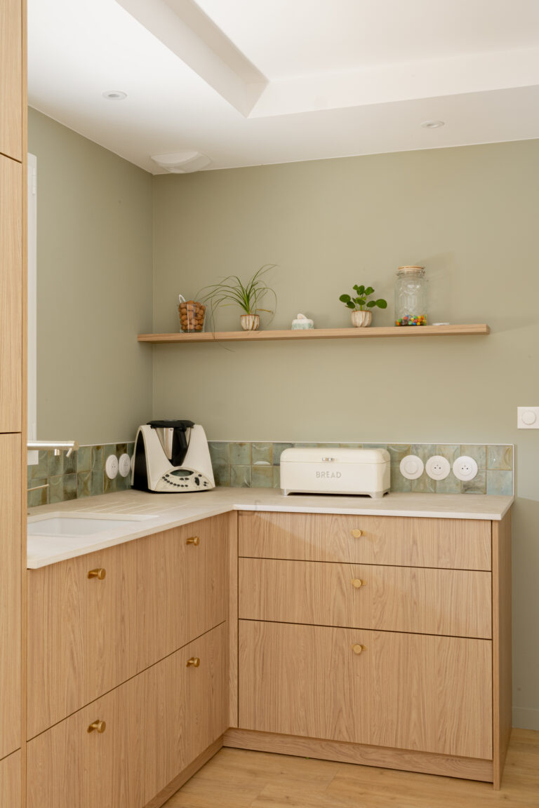 Détail de cuisine en bois aux angles arrondis et crédence verte, rénovation à Mauléon